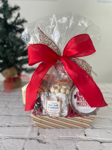 Wrapped gift basket with bow in front of Christmas tree. Wrapped gift basket with bow in front of Christmas tree.