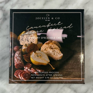 Dark square box with picture of board with cheese, bread, salami, pear and bottle of wine