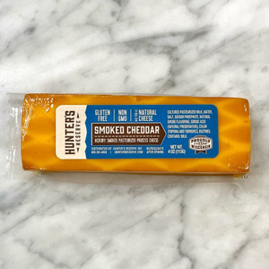 a marble countertop with a bar of cheese on top. the cheese is a dark orange with light streaks in it. Blue label on the cheese with the product information
