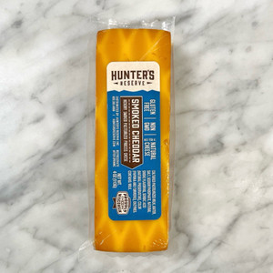 a marble countertop with a bar of cheese on top. the cheese is a dark orange with light streaks in it. Blue label on the cheese with the product information