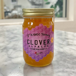 Small, oblong glass jar with a gold lid. a pink honeycomb-like label reads the company name and product flavor
