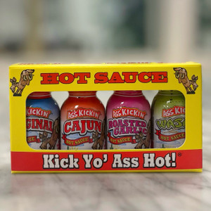 a yellow rectangular box with a large window in the middle. reading "Hot Sauce" across the top above the window with a bucking donkey on either side of the words. A red banner across the bottom below the window with white text reading "Kick Yo' Ass Hot!". The window shows the four small bottles within the package