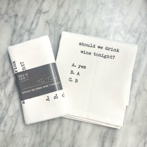a marble countertop with a white towel laying on top on it, folded in half with the text in a typewriter font. For the full text please see product description. Next to the towel is the folded version of the same towel with a gray band around it with the Dev D and Co. logo