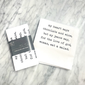 a marble countertop with a white towel laying on top on it, folded in half with the text in a typewriter font. For the full text please see product description. Next to the towel is the folded version of the same towel with a gray band around it with the Dev D and Co. logo