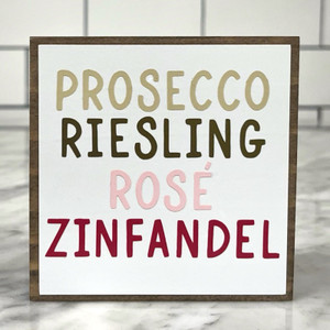 Square wood block with white background with "Prosecco, Riesling, Rose, and Zinfandel" in different wine colors