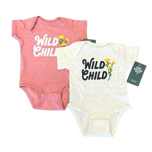 A light tan and a salmon colored infant onsies with "wild child" printed in black lettering and small yellow and green flowers
