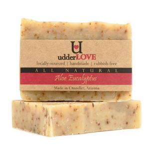 Light tan bar of soap with specks of aloe and eucalyptus with tan paper wrapping as label