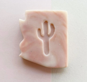 light pink bar of soap in the shape of Arizona with a cut of shape of a saguaro cactus in the middle