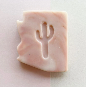 light pink bar of soap in the shape of Arizona with a cut of shape of a saguaro cactus in the middle