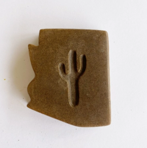 dark brown bar of soap in the shape of Arizona with a cut out shape of a saguaro cactus in the middle