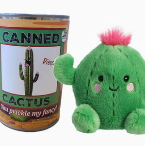 Plush barrel cactus with arms, legs, eyes and pink puff of hair next to a yellow and green can displaying the front label with black lettering