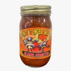 A tall cylindrical glass jar with gold lid containing red salsa; the label says “Sting N Linger Salsa” across the top in yellow font, the companies logo of two cowboy-like bee’s in the middle