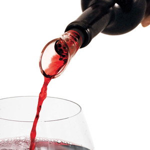 pour spout in the neck of an open wine bottle pouring red wine into a wine glass