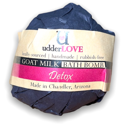 Round bath bomb wrapped in black paper packaging with tan paper wrapping for a label with dark pink writing