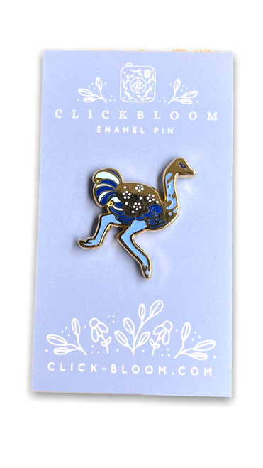Enamel pin in the shape of a ostrich in shades of blue and gold.