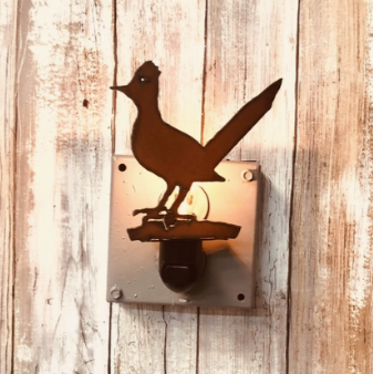 Rustic iron cutout in the shape of a roadrunner as a nightlight with a wood background.