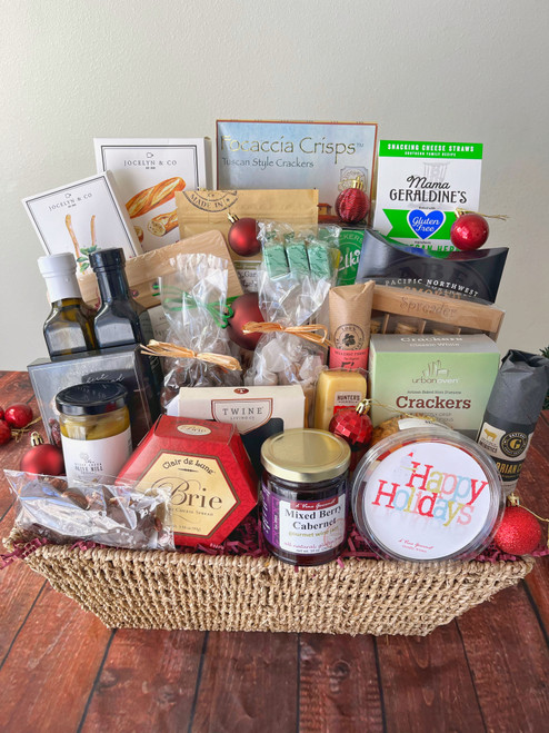 A woven brown basket with burgundy filling and products standing in it. Red ornaments are placed in and around the basket.