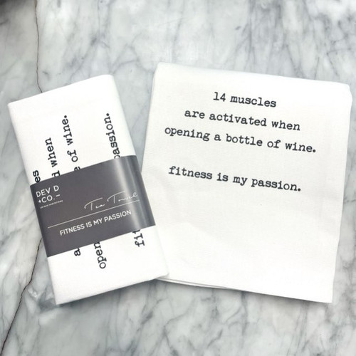 a marble countertop with a white towel laying on top on it, folded in half with the text in a typewriter font. For the full text please see product description. Next to the towel is the folded version of the same towel with a gray band around it with the Dev D and Co. logo a marble countertop with a white towel laying on top on it, folded in half with the text in a typewriter font. For the full text please see product description. Next to the towel is the folded version of the same towel with a gray band around it with the Dev D and Co. logo