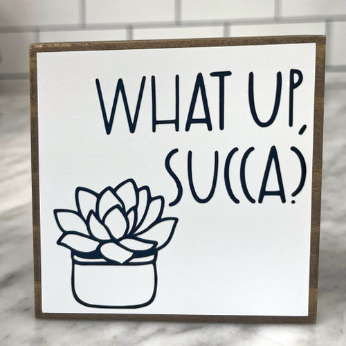 Square wood block with black lettering and drawing of a potted succulent. 