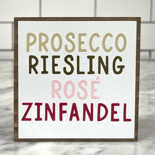 Square wood block with white background with "Prosecco, Riesling, Rose, and Zinfandel" in different wine colors