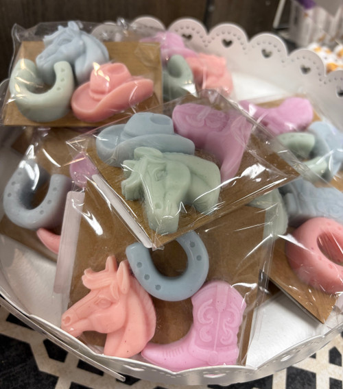 White bowl with multiple packages of mini soaps in a variety of colors and shapes