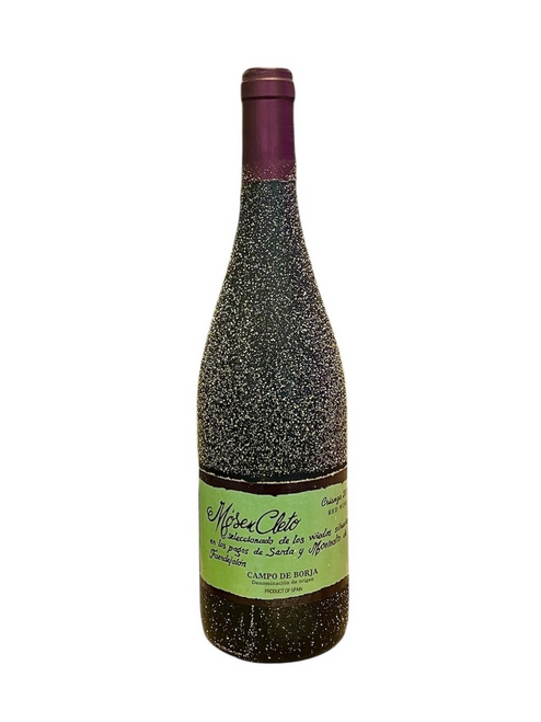Dark glass wine bottle lightly covered with dirt from the vineyard with a green label