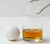 Golf ball ice mold next to a glass with brown liquid and golf ball shaped ice cube in tongs
