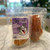 Clear plastic resealable food pouch showing contents of light brown dog treats with purple and white front label