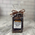 Clear cello food bag showing contents of dark chocolate bark with square white front label tied with a bow.