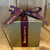 Closed glossy gold gift box with burgundy ribbon with "Made in Arizona" in gold lettering on the ribbon