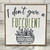 Square wood block with white background, black and green lettering, and a drawing of a pot of succulents. 