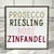 Square wood block with white background with "Prosecco, Riesling, Rose, and Zinfandel" in different wine colors