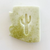 off white bar of soap with green flecks, in the shape of Arizona with a cut out in the middle in the shape of a saguaro cactus