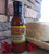 Glass bottle with red colored ketchup displayed in front of brick wall with cowboy hat