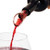 pour spout in the neck of an open wine bottle pouring red wine into a wine glass