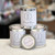 Round tin with lid and white label with black lettering Round tin with lid and white label with black lettering