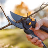 A hand cutting a bare branch with the Heavy Duty Bypass Pruner at sunset