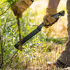 A gloved hand cutting through a sapling at ground level with the Super Duty Brush Axe