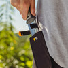 A hand drawing the Hori Hori Garden Knife from its belt sheath