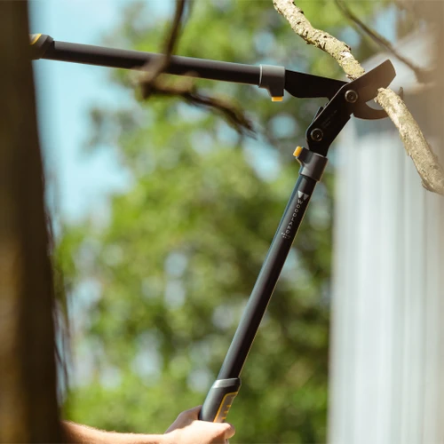A hand cutting a branch overhead with the Super Duty MaxForce Lopper