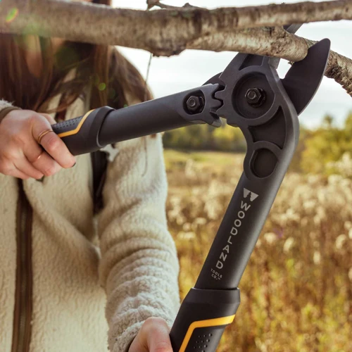 A person cutting an overhead branch with the Compact Duralight Lopper in a field