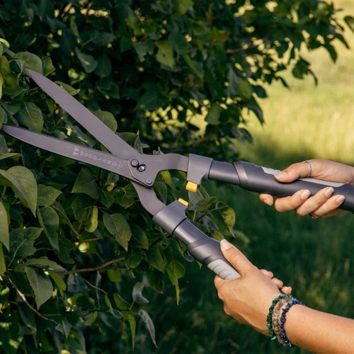 Hands trimming a leafy shrub with the Heavy Duty LeverAction Hedge Shear