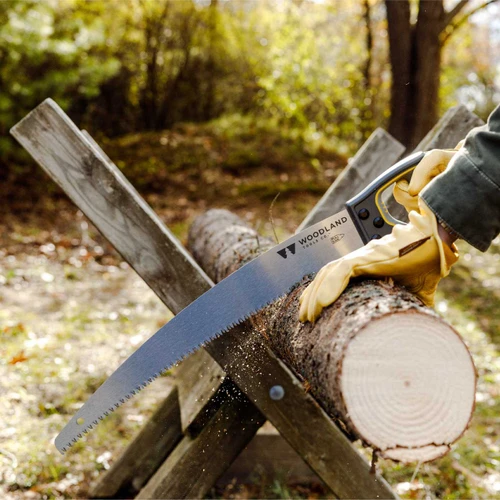 A gloved hand cutting a log on a sawbuck with the Super Duty D-Handle Saw