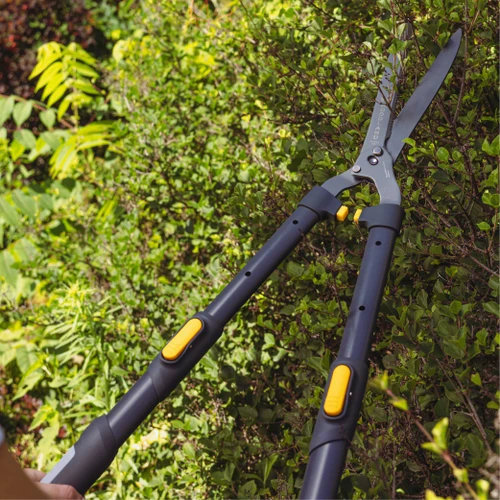 The Extendable LeverAction Hedge Shears trimming a green hedge in sunlight