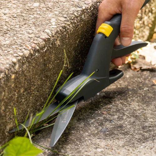 A hand trimming grass along a concrete edge with the Regular Duty Grass Shears