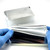 Holding PCRSEAL-ALM aluminum foil sealing film with gloved hands next to sealed deep-well plate
