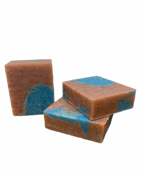 The image depicts three bars of blue & brown marbled soap on a field of plain white. Two bars are lying flat and stacked on top of each other, one slightly off-center from the other. The third bar is standing vertically on its end, to the left of them.
