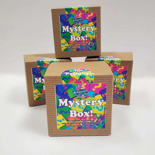 A stack of four mystery boxes, three arranged on the bottom with a fourth resting on top. Brown kraft paper boxes with very colorful labels.