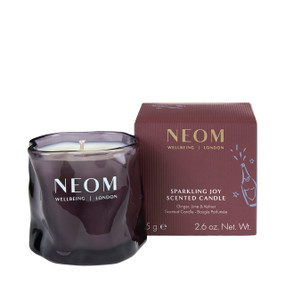 NEOM Sparkling Joy scented candle in purple ripple glass jar next to maroon product box