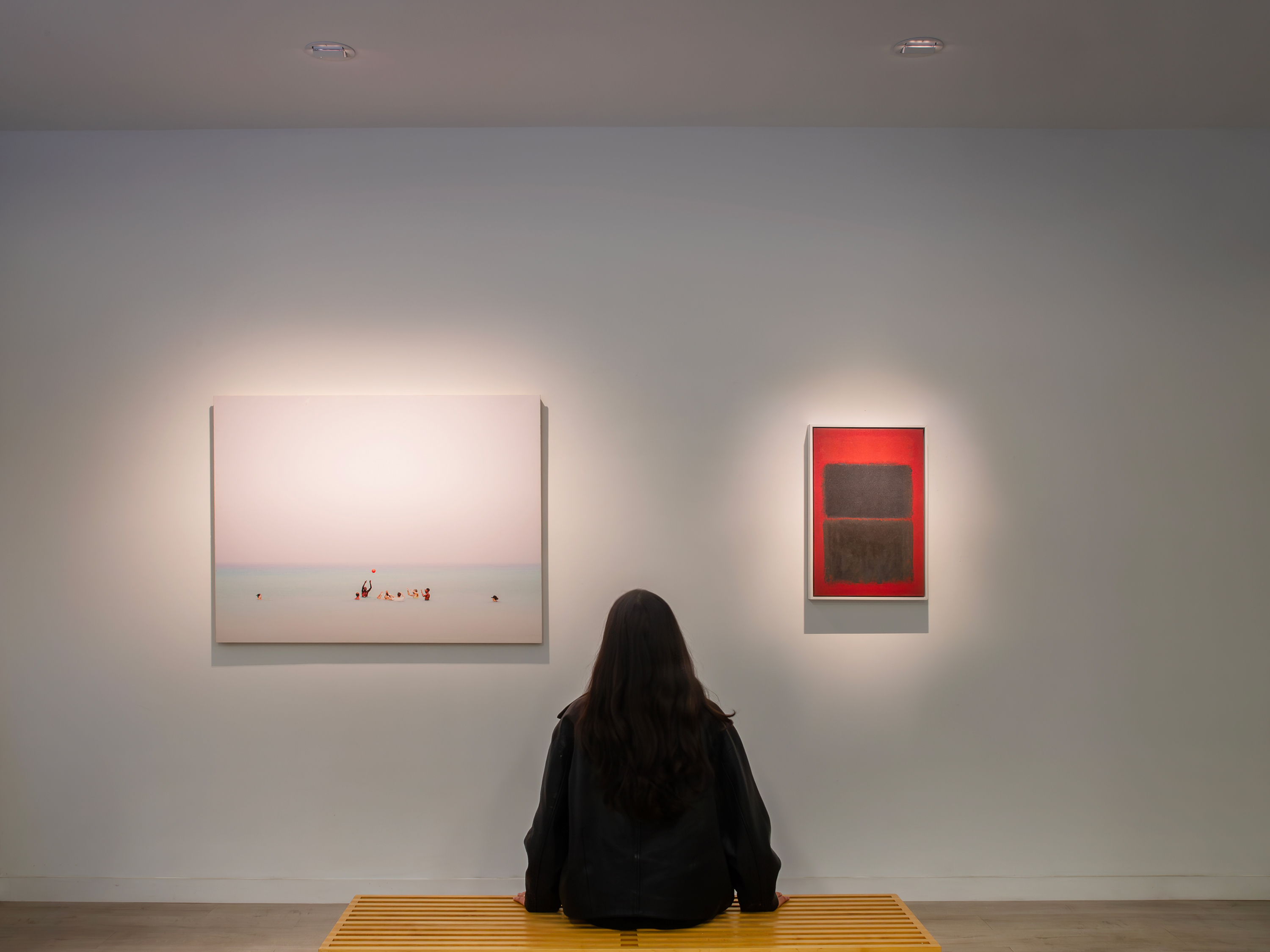 Paintings on wall and woman on bench illuminated by Revelite CL